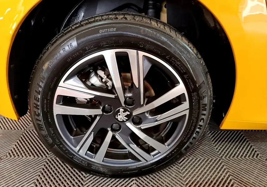 Gros plan sur la roue avant droite de la Peugeot 208 jaune 2023, avec jante alliage et pneu Michelin visible.