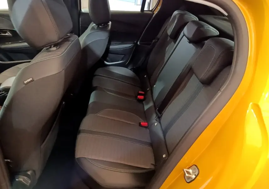 Vue intérieure côté droit des sièges arrière noirs d'une Peugeot 208 jaune 2023 avec portière ouverte.