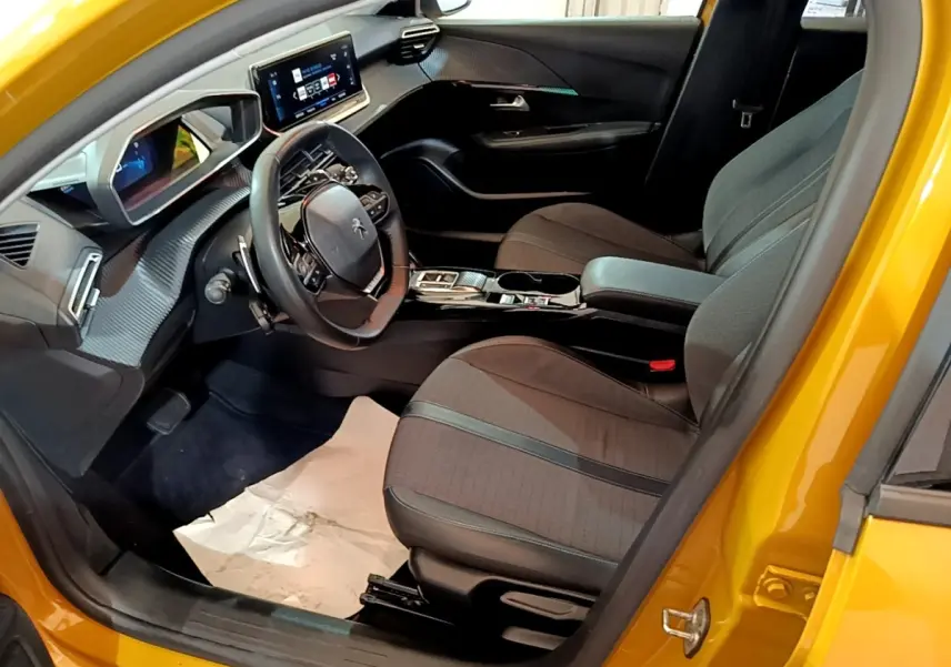 Intérieur côté conducteur d'une Peugeot 208 jaune 2023, montrant le volant cuir multifonctions et l'écran tactile central.