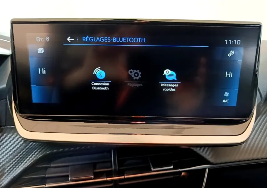 Écran tactile central de la Peugeot 208 jaune 2023 affichant les réglages Bluetooth, vue intérieure frontale.