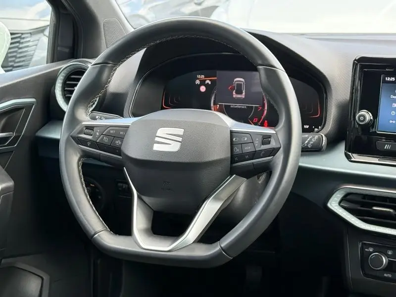 Vue rapprochée du volant multifonction du SEAT Arona 2025, avec tableau de bord numérique et commandes intégrées.