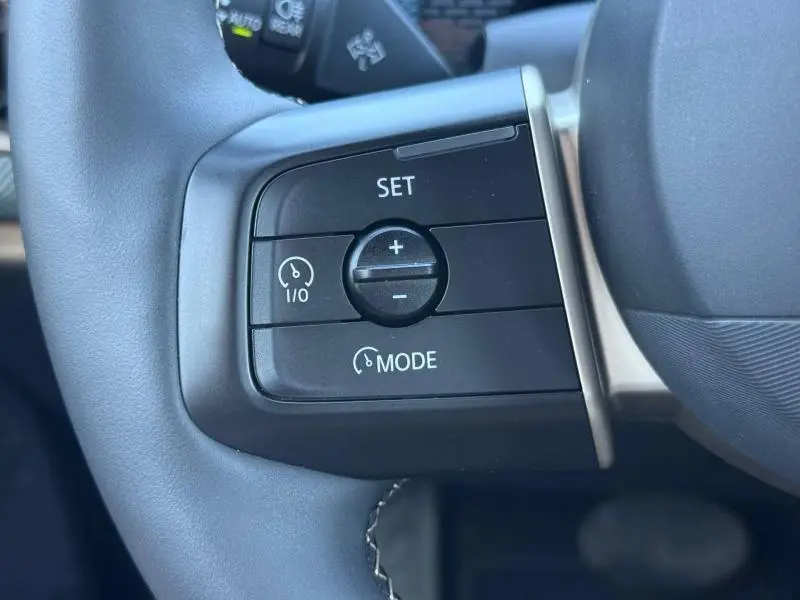 Gros plan sur les commandes de régulateur de vitesse au volant du MINI COUNTRYMAN 2024 en finition Midnight Black II.