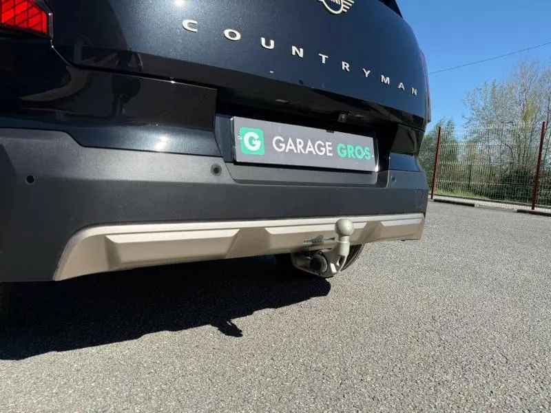 Vue rapprochée de l'arrière droit d'une MINI Countryman 2024 Midnight Black II avec attelage visible.