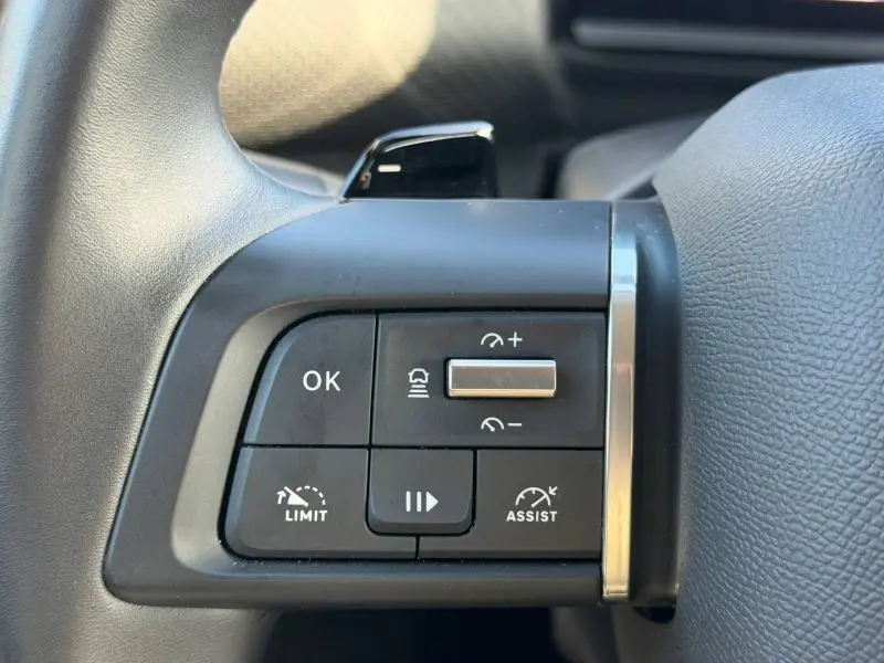 Gros plan sur les commandes au volant côté gauche du Citroën C4 X noir 2024, avec boutons de régulateur et assistant de conduite.