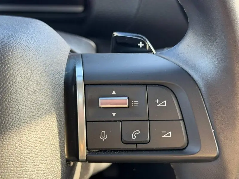 Gros plan sur les commandes au volant côté gauche du Citroën C4 X noir 2024, avec boutons de volume et appel.