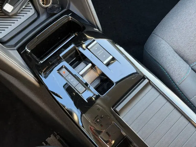 Vue en plongée sur la console centrale noire brillante du Citroën C4 X 2024, avec commandes de boîte automatique et bouton Drive Mode.