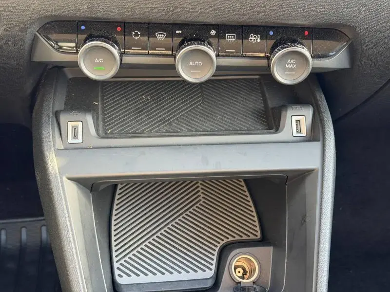 Gros plan sur la console centrale du Citroën C4 X 2024 noire, montrant les commandes de climatisation automatique et ports USB.
