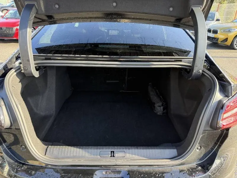 Coffre ouvert vu de l'arrière d'une Citroën C4 X noire 2024, montrant un espace de chargement vide et propre.