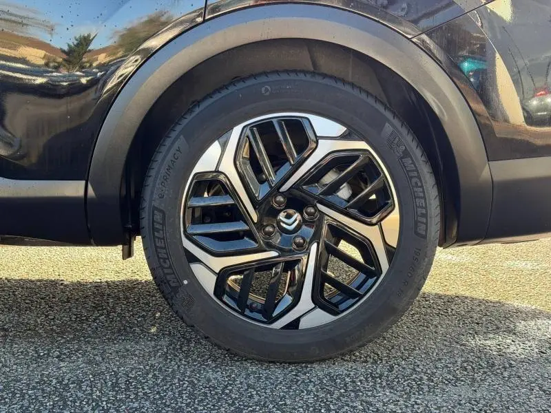 Gros plan sur la roue avant gauche noire du Citroën C4 X 2024 avec jante alliage au design géométrique.