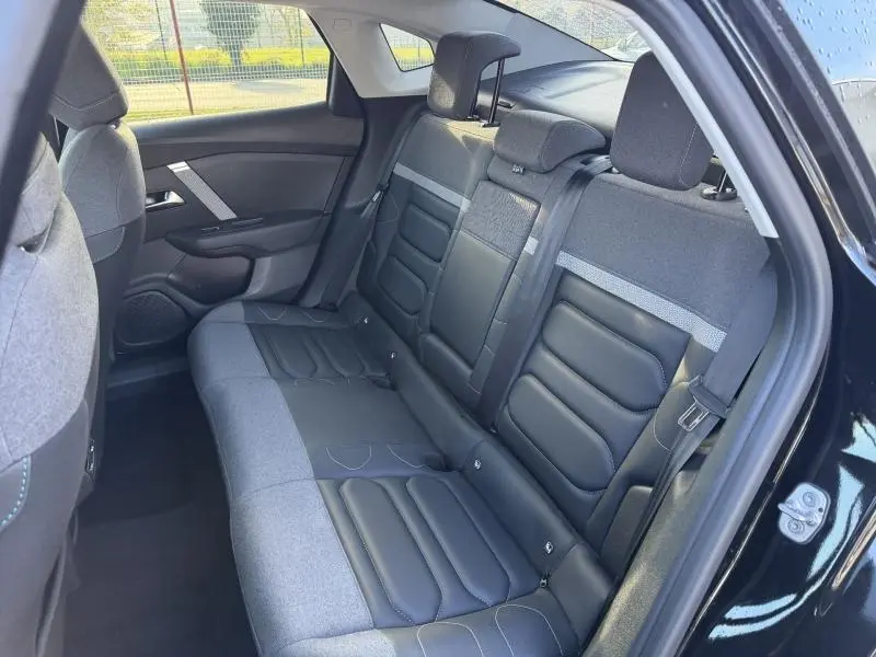 Vue intérieure du siège arrière côté droit de la Citroën C4 X 2024 noire, avec sellerie mixte tissu et cuir noir.