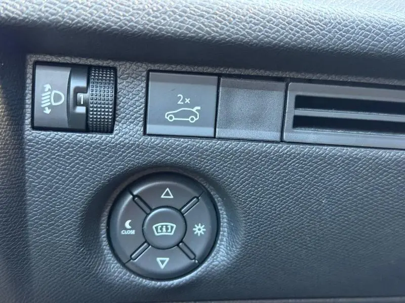 Détail du tableau de bord noir de la Citroën C4 X 2024 montrant les commandes d'éclairage et d'ouverture du coffre.