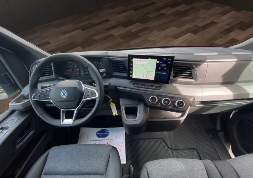 Vue intérieure avant du tableau de bord gris et volant Renault avec écran tactile central et commandes climatisation.