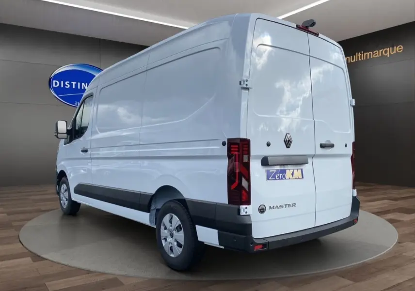 Vue 3/4 arrière droite d’un Renault Master blanc 2025 avec feux arrière LED et logo distinctif sur porte arrière.