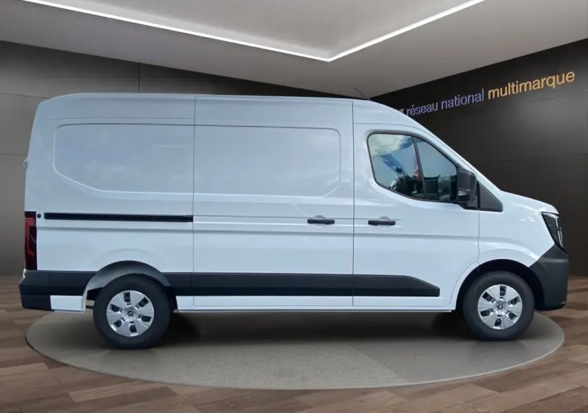 Vue de profil côté droit d’un Renault Master blanc avec bande noire basse et jantes argentées, en showroom intérieur.