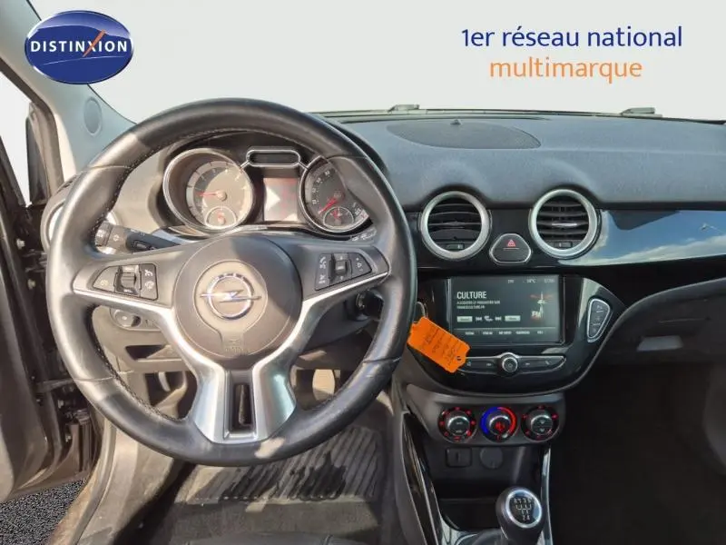 Vue intérieure avant de l'Opel Adam marron, volant cuir multifonction et tableau de bord avec écran tactile et commandes clim.