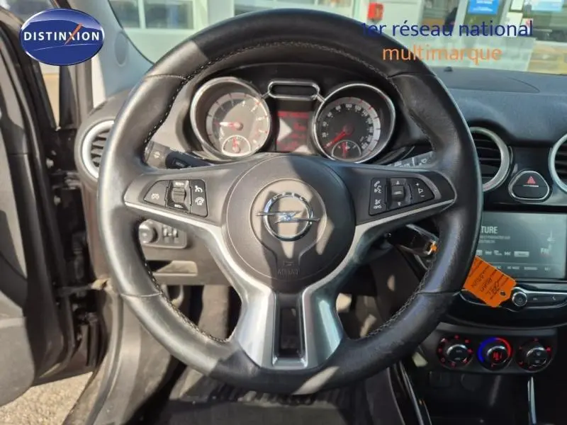 Vue rapprochée du volant cuir multifonction noir de l’Opel Adam 2017 avec tableau de bord et console centrale visibles.
