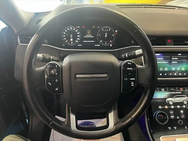 Vue intérieure centrée sur le volant noir du Range Rover Evoque 2020 avec tableau de bord digital et écran tactile.