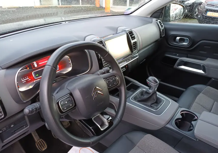 Intérieur du Citroën C5 Aircross gris platinium, vue côté conducteur sur le tableau de bord et levier de vitesses manuel.