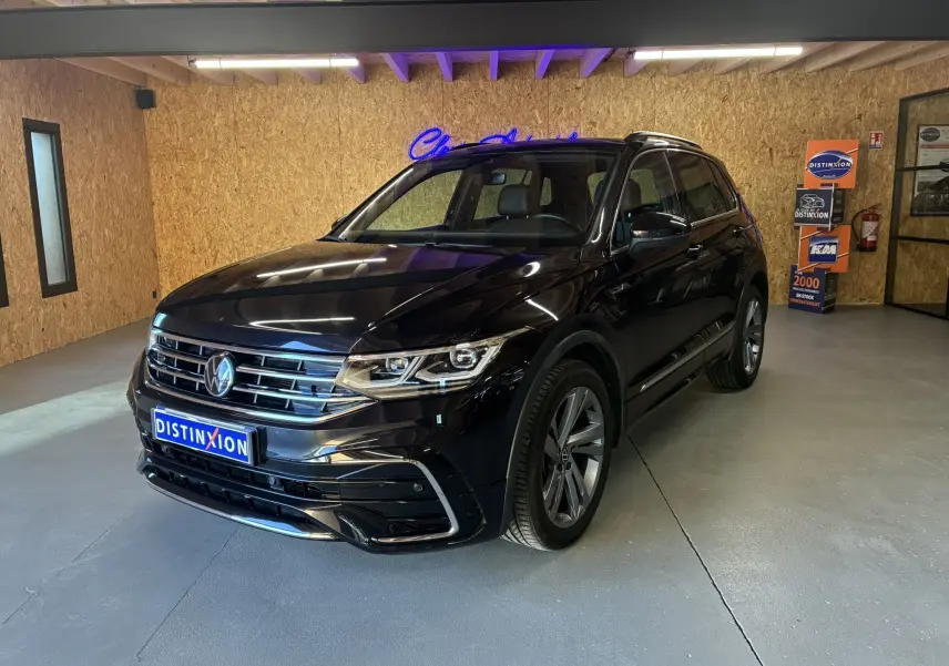Volkswagen Tiguan noir en 3/4 avant droit dans un showroom avec jantes alu et calandre chromée.