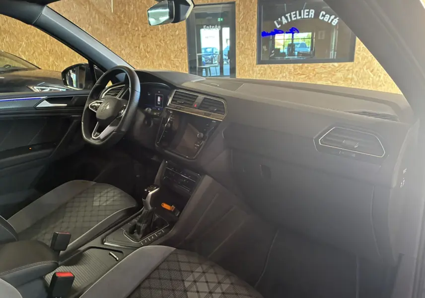 Intérieur noir du Volkswagen Tiguan 2022, vue côté conducteur, volant multifonctions et sièges sport en tissu.