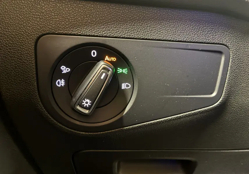 Gros plan sur le sélecteur de phares noir avec fonction automatique dans l'habitacle du Volkswagen Tiguan noir 2022.