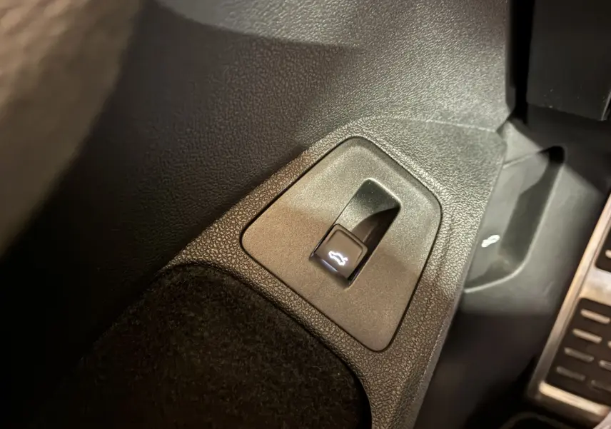 Gros plan sur le bouton d'ouverture du coffre dans l'habitacle noir du Volkswagen Tiguan 2.0 TDI 2022.