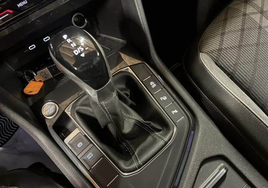 Gros plan sur la console centrale du Volkswagen Tiguan noir, mettant en valeur le levier de vitesse automatique et les commandes d'assistance.
