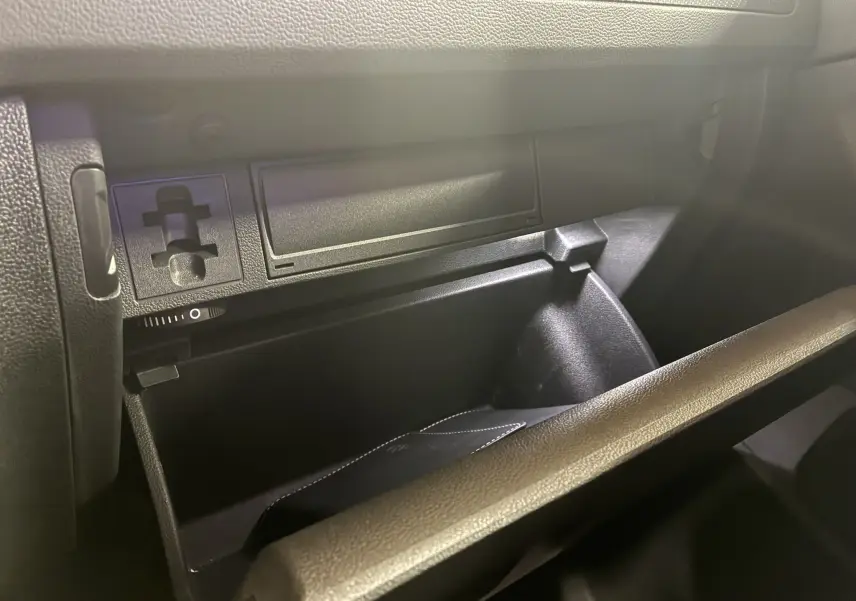 Gros plan sur la boîte à gants noire ouverte du Volkswagen Tiguan 2.0 TDI 150 DSG7 R-Line 2022, intérieur sombre.