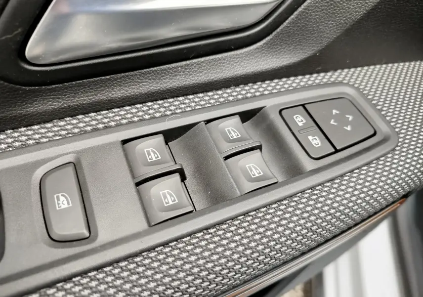 Gros plan sur les commandes de lève-vitres et réglage des rétroviseurs côté conducteur d'une Dacia Sandero Stepway 2021.