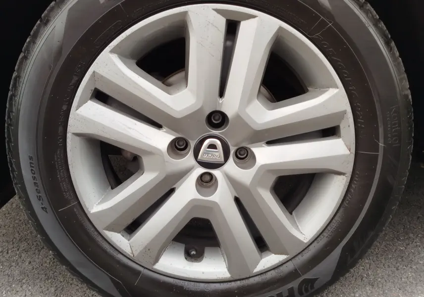 Gros plan sur la jante argentée et le pneu 4 saisons d'une Dacia Sandero Stepway blanc glacier.