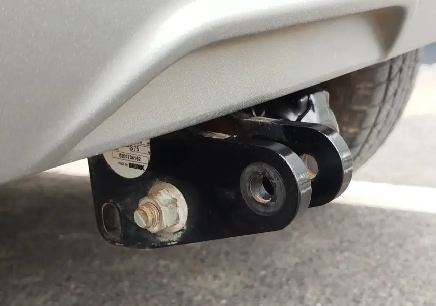 Gros plan sur l'attelage noir fixé sous le pare-chocs blanc glacier arrière d'une Dacia Sandero Stepway 2021.