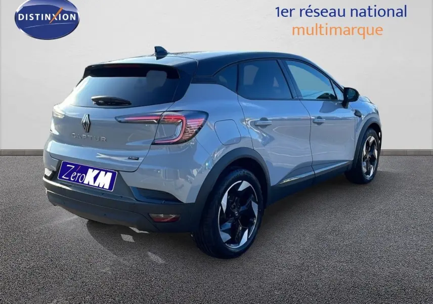 Vue 3/4 arrière droite d'un Renault Captur E-Tech hybride gris Rafale métal avec toit noir et jantes bicolores.