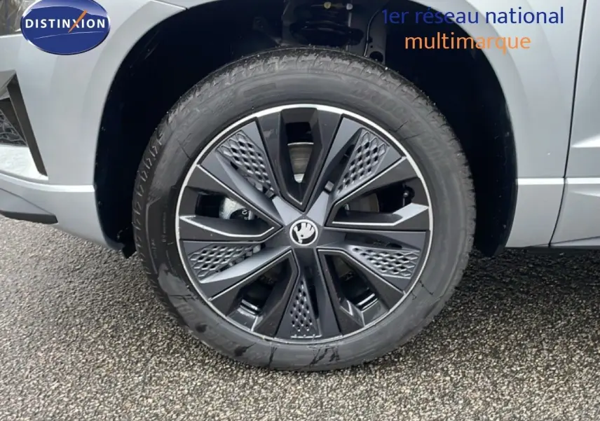 Gros plan sur la roue avant droite gris argent métallisé du Skoda Karoq 2025 avec jante noire et argentée au design moderne.