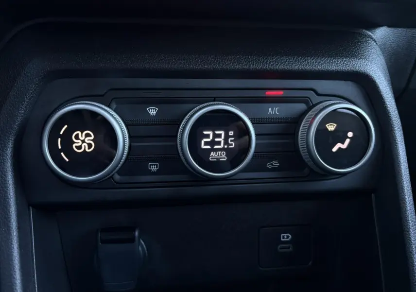 Gros plan sur la commande de climatisation automatique du Dacia Jogger gris Schiste, avec affichage digital à 23,5°C.