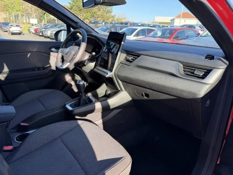 Intérieur de Renault Captur 2025 vu côté conducteur, avec tableau de bord moderne et levier de vitesse manuel, portières Rouge Flamme visibles.