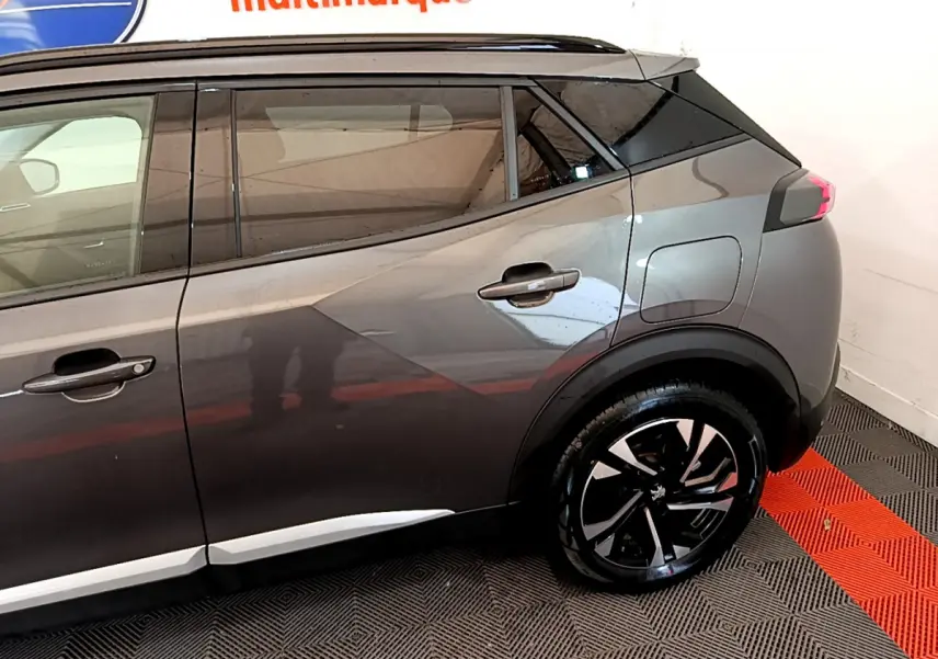 Vue latérale côté droit sur l'arrière d'un Peugeot 2008 gris foncé avec jante alliage noire et toit noir.