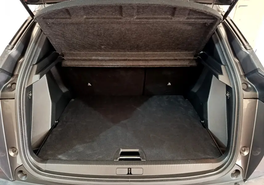 Coffre ouvert vu de l'arrière d'un Peugeot 2008 gris foncé, montrant l'espace de chargement vide et la tablette relevée.