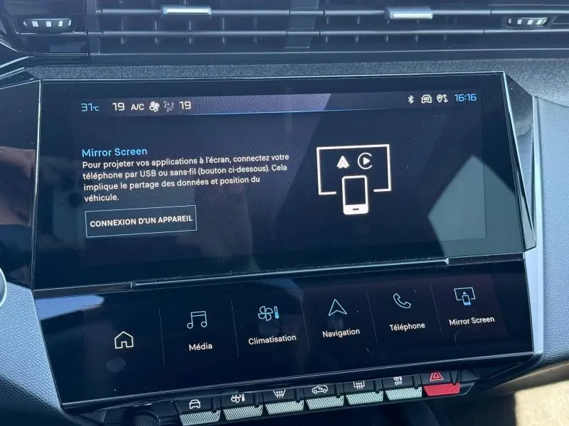Écran tactile central du tableau de bord de la Peugeot 308 gris 2025, affichant les options multimédia et climatisation.