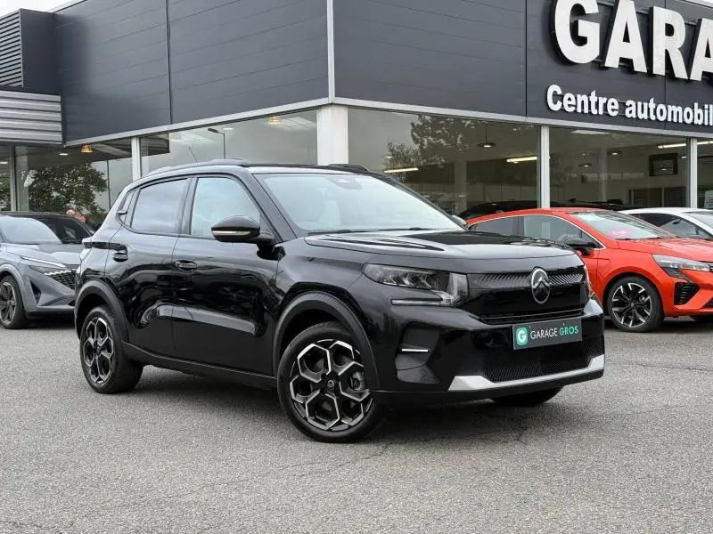 Citroën C3 électrique noir Perla Nera en 3/4 avant droit, avec jantes spécifiques et calandre moderne, devant un garage.