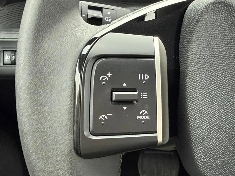 Gros plan sur les commandes de régulateur de vitesse à gauche du volant d’une Citroën C3 électrique Noir Perla Nera.