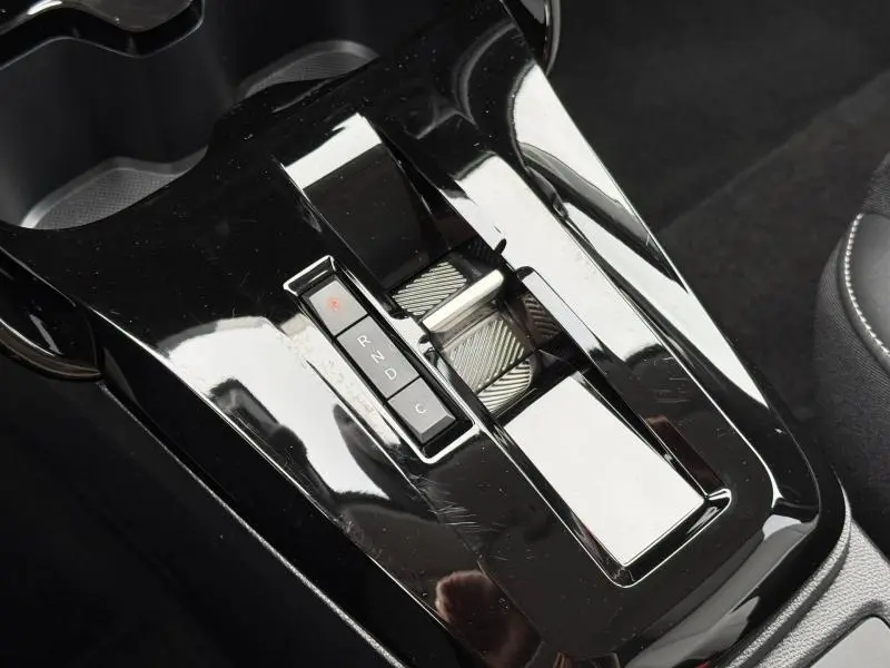 Gros plan sur la console centrale noire brillante de la Citroën C3 électrique 2025 avec sélecteur de boîte automatique.