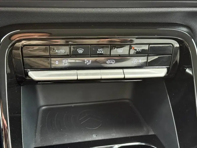 Vue rapprochée de la console centrale noire avec commandes climatisation et zone de rangement du Citroën C3 électrique 2025.