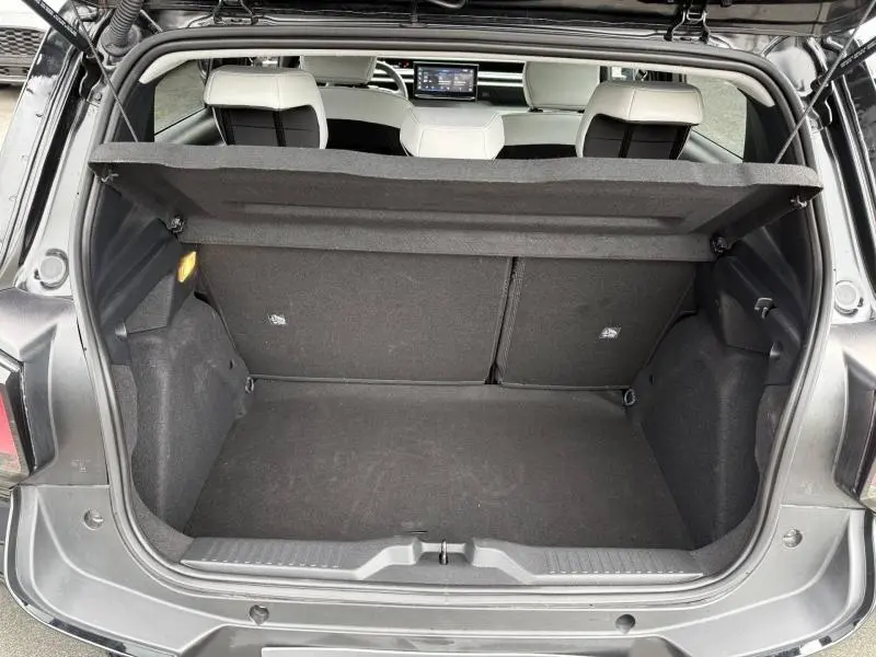 Coffre ouvert vu de l'arrière d'une Citroën C3 électrique 2025 noir Perla Nera avec banquette arrière et tablette tactile visibles.