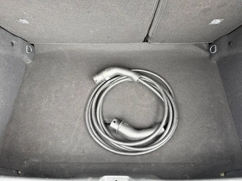 Coffre ouvert d’une Citroën C3 électrique 2025 noir Perla Nera avec câble de recharge enroulé visible.