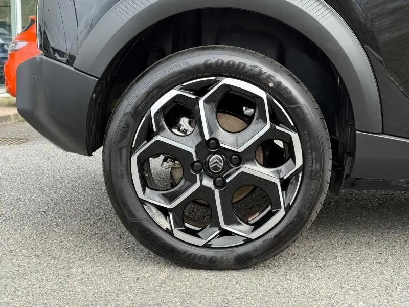 Gros plan sur la roue avant droite de la Citroën C3 électrique 2025 en Noir Perla Nera avec jante noire et argentée.