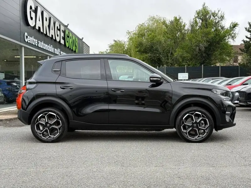 Vue latérale droite d'une Citroën C3 électrique 2025 en noir Perla Nera avec jantes au design hexagonal distinctif.