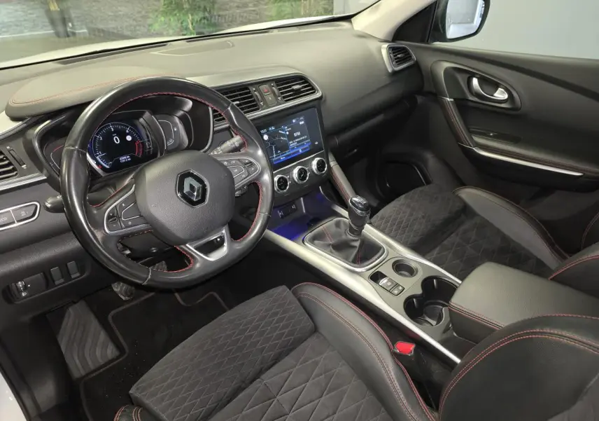 Vue intérieure côté conducteur du Renault Kadjar 1.5 Blue dCi 115 Black Edition avec sellerie noire et surpiqûres rouges.