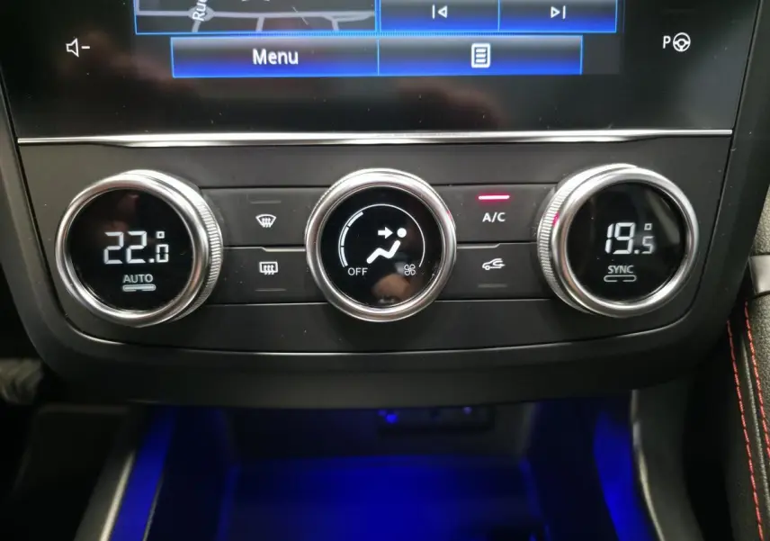 Gros plan sur la console centrale du Renault Kadjar blanc, montrant les commandes de climatisation avec éclairage bleu ambiant.