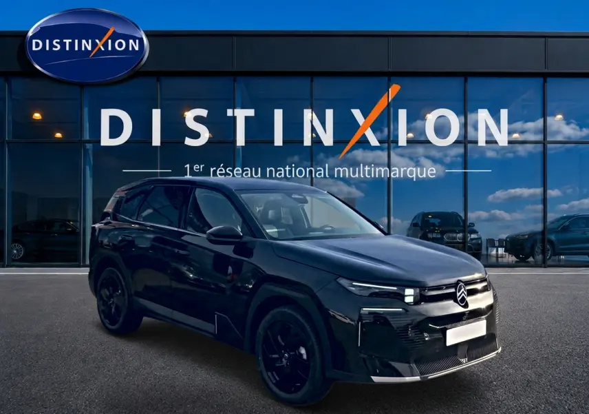 Citroën C5 Aircross noir vue 3/4 avant droit, jantes noires, devant vitrine Distinxion reflet ciel bleu.