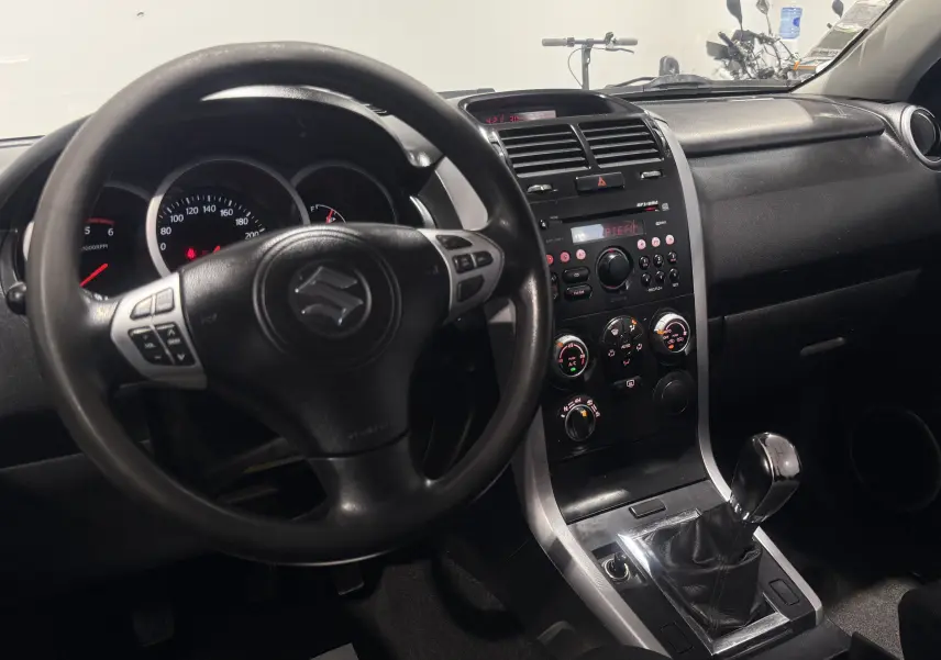 Intérieur du Suzuki Grand Vitara 2007, vue du poste de conduite avec volant, tableau de bord et levier de vitesses manuel.